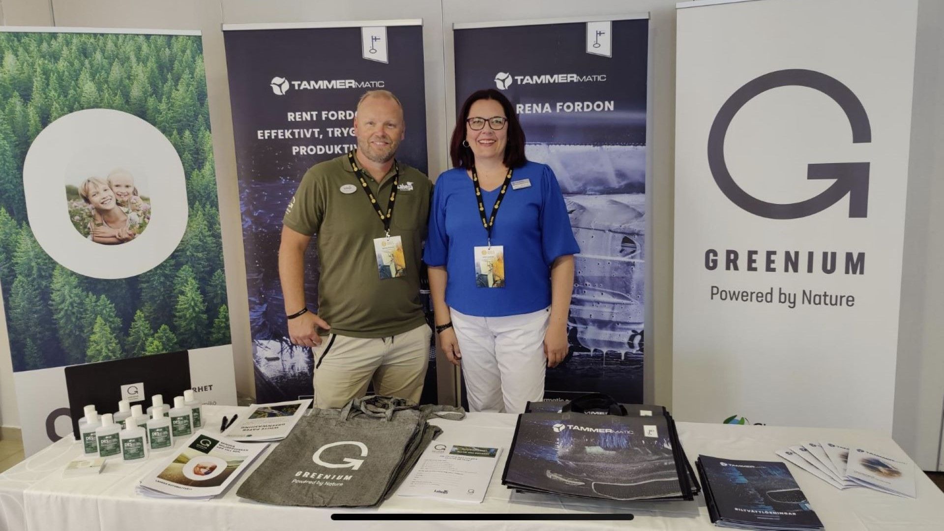 Två säljare som står vid ett bord på en mässa