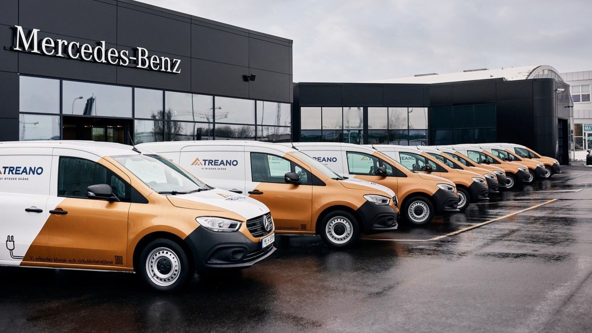 Ran rad med Mercedes-Benz bilar utanför en byggnad med en Mercedes-Benc logga på väggen